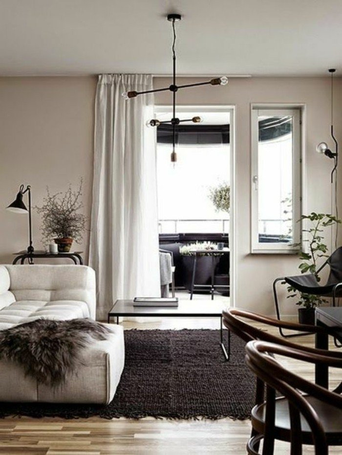 espacio decorado en color gris perla, suelo de madera con alfombra en gris oscuro, sofá blanca y cortinas blancas 