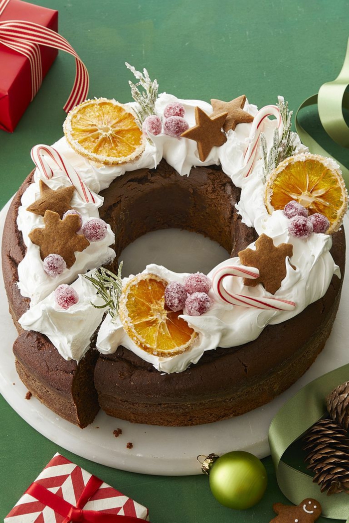 tarta de chocolate decorada con nata, galletas jengibre, rebanadas de naranja y frutas azucaradas 