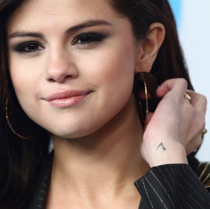 pequeños detalles tatuados en la muñeca, tatuajes pequeños mujer, Selena Gomez con una pequeña nota musical en la muñeca 