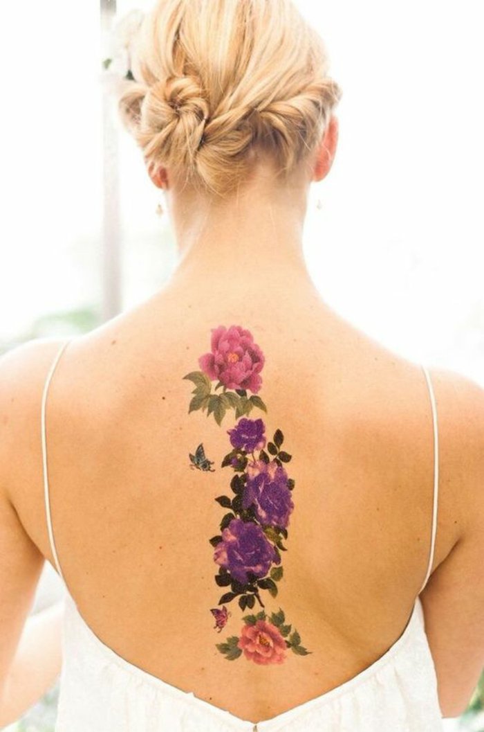 adorable diseño con flores en rosado y lila en la espalda, tatuajes de flores bonitos para mujeres 