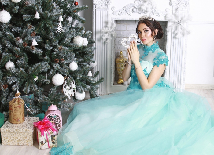 mujer con precioso vestido de tul azul, árbol navideño grande decorado de bolas en blanco 