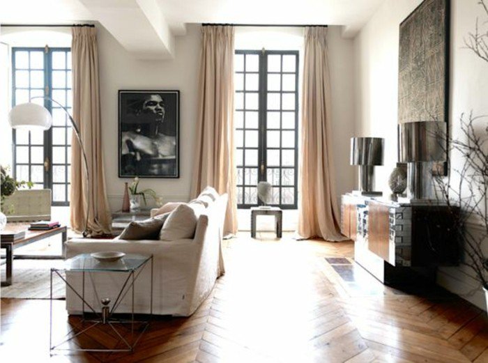 grande salón decorado en colores claros, cortinas largas en beige, suelo de parquet, sofá blanca 