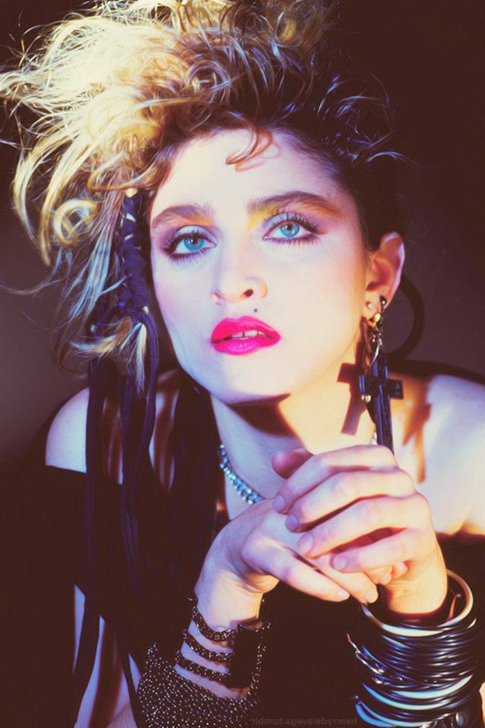 Madonna con un outfit moda de los 80, blusa negra, muchas pulseras, grandes pendientes en forma de cruz 