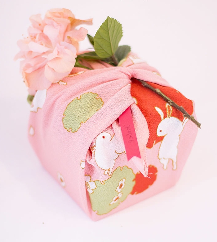 regalos bonitos envueltos en tela, pequeño detalle en colores pastel, caja de regalos con una flor 