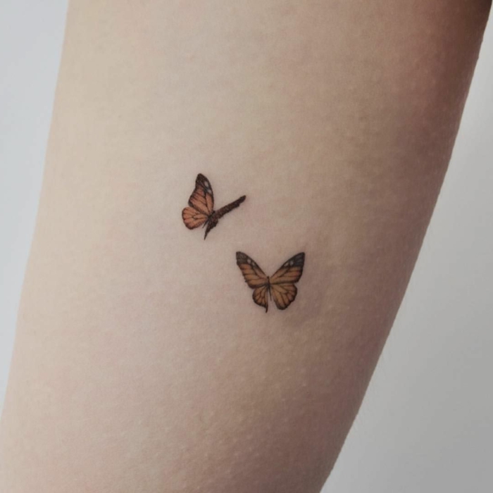 dos pequeñas mariposas color naranja tatuados en el antebrazo, tatuajes bonitos en fotos 