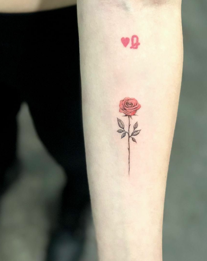 pequeño detalle en color rojo tatuado en el antebrazo, tatuajes con un fuerte significado, tattoos con rosas para hombres y mujeres 