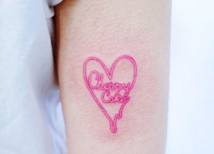 tatuajes de corazones super bonitos, diseños de tatuajes mujer en el brazo, precioso corazón en color rosado con letras 