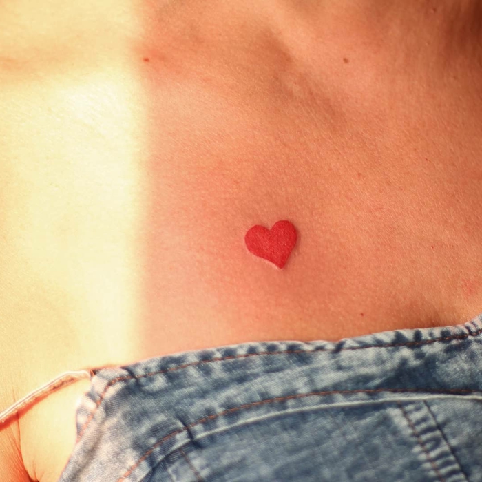 pequeño tatuaje en el pecho, corazón pequeño color rojo, diseños de tatuajes de corazones para mujeres 