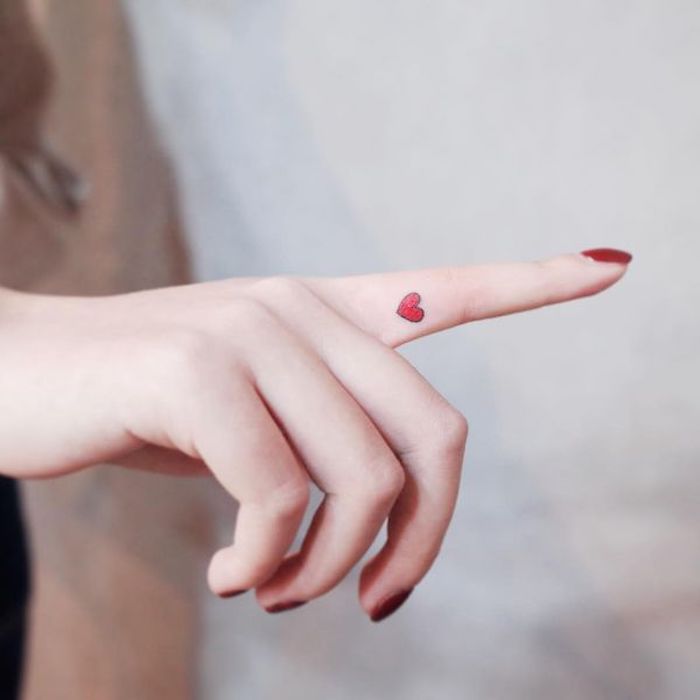 pequeño corazón rojo tatuado en el dedo indice, tatuajes para dedos bonitos y femeninos 