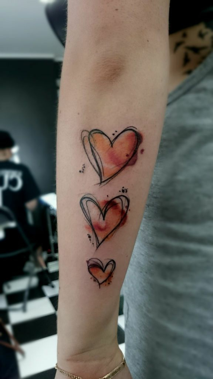 tres corazones de diferente tamaño tatuados en el antebrazo, tatuajes originales con corazón y sus significados 