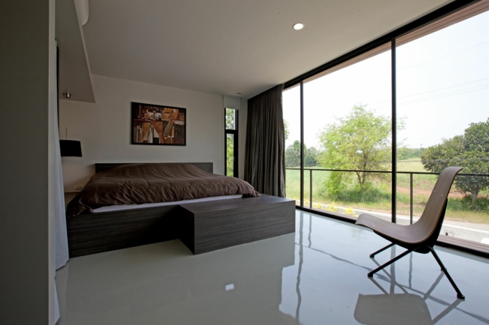 dormitorio en estilo minimalista con grandes ventanales, cama doble, luces empotradas y muebles de diseño 