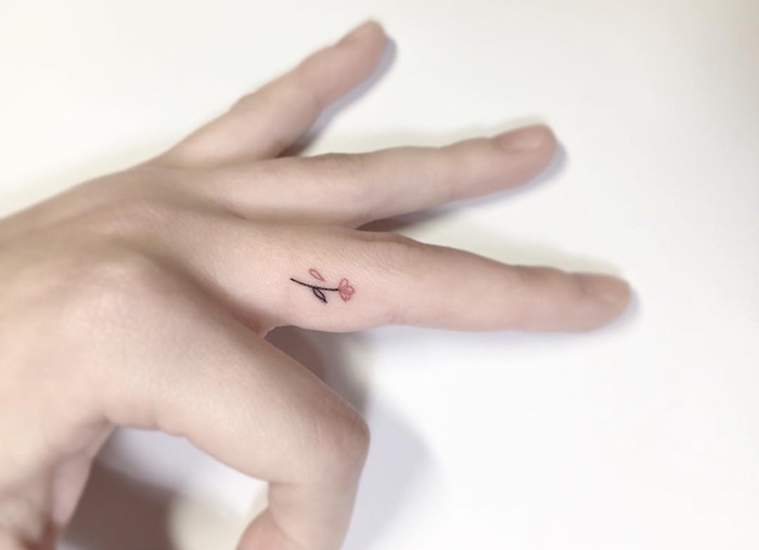 delicada y bonita flor tatuada en el dedo corazón, imagines de tatuajes pequeños para dedos