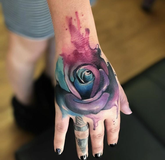 precioso tatuaje con pintura acuarela, grande rosa tatuada en la mano, significado de tatuajes
