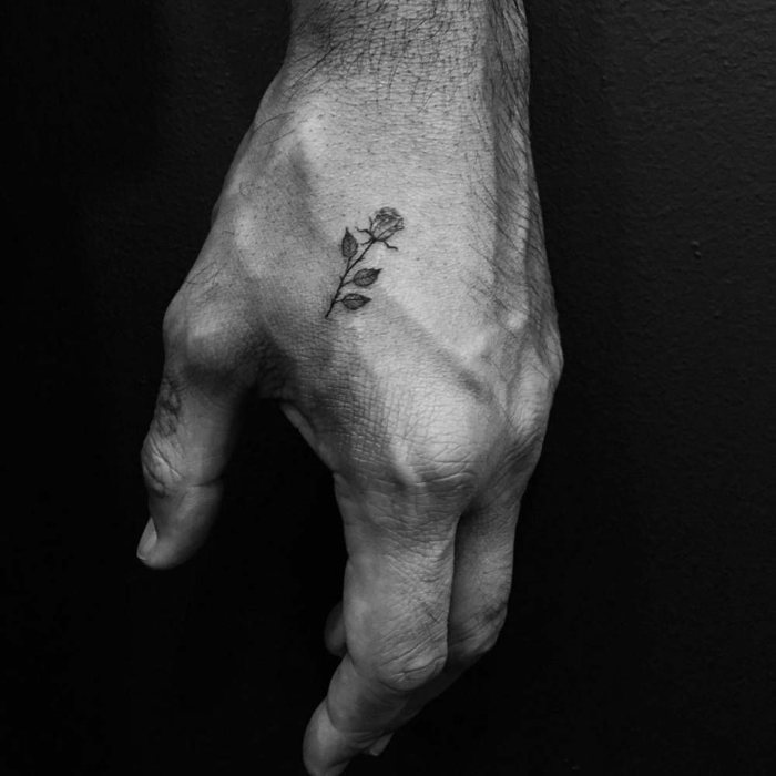 significado de tatuajes con flores, pequeña rosa tatuada en la mano, tatuajes simbólicos para hombres y mujeres 
