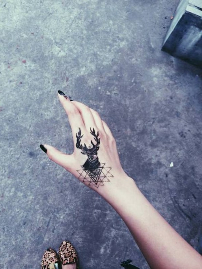 diseños de tattoos en la mano originales, tatuaje negro con reno en la mano, tatuajes simbólicos 