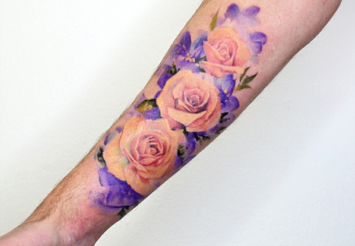 diseños de tatuajes bonitos con flores para hombres y mujeres, tattoo en color rosado y lila en el antebrazo 