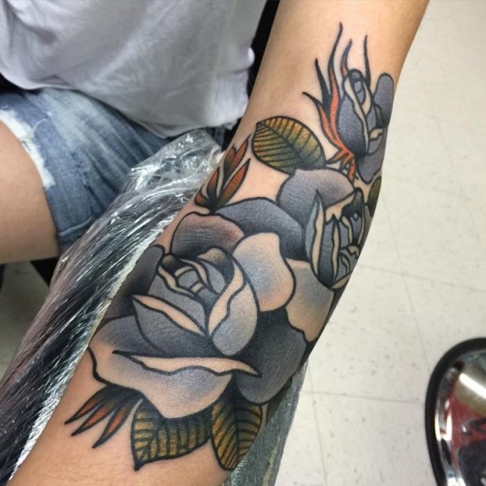 tatuaje en el antebrazo bonito con flores, precioso diseño con rosas con azul en elantebrazo, significado tattoos de flores 