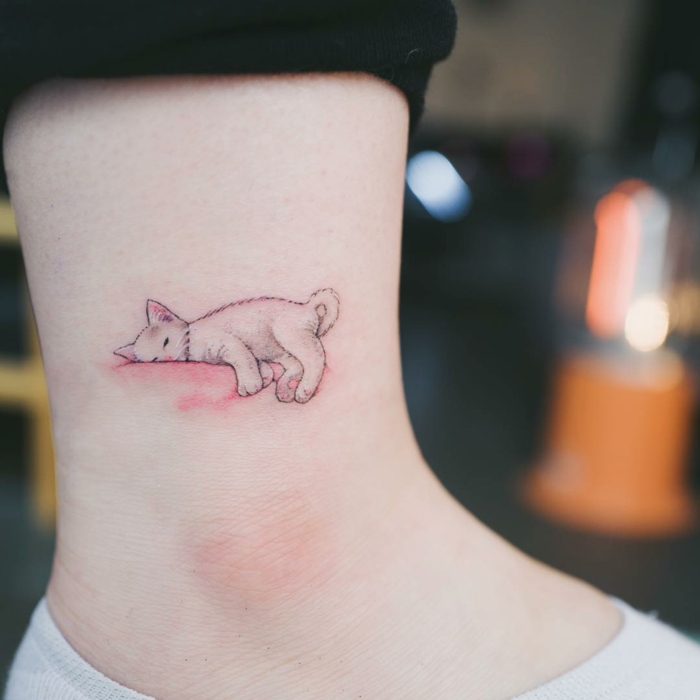adorables propuestas de tatuajes de animales, pequeño gato dormido tatuado en el tobillo, diseños de tatuajes minimalistas 