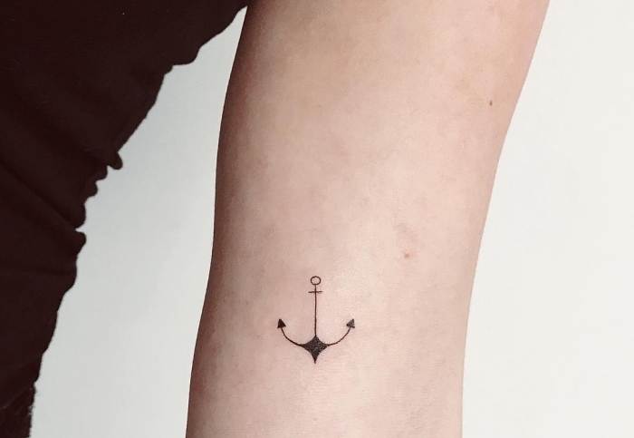 fotos de tattoos pequeños en el brazo, pequeña ancla tatuada en el brazo con tinta negra, pequeños detalles simbolicos en tatuajes 