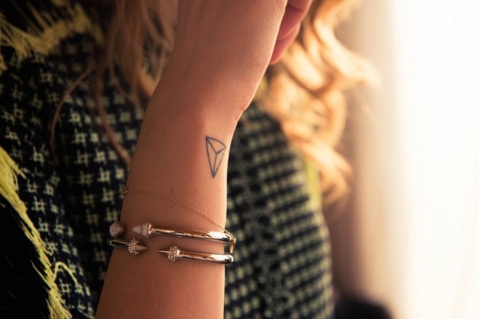 pulsera-color-plateado-tatuaje-triangulo-3d-en-la-muñeca-tattoos-en-el-antebrazo-mujer-pelo-rubio-rizado-fotos-de-tatuajes ideas de tatuajes geometricos en el antebrazo, diseños de tatuajes bonitos, tatuajes de mujer tatuajes elegantes