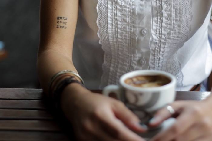 taza-de-cafe-mujer-con-pequeño-tatuaje-en-el-brazo-ideas-de-tatuajes-con-letras-mujer-pulseras-tatuajes-en-el-brazo-mujer frase en inglés tatuada en el brazo, galería de tatuajes con letras, tatuajes de mujer tatuajes elegantes, diseños minimalsitas