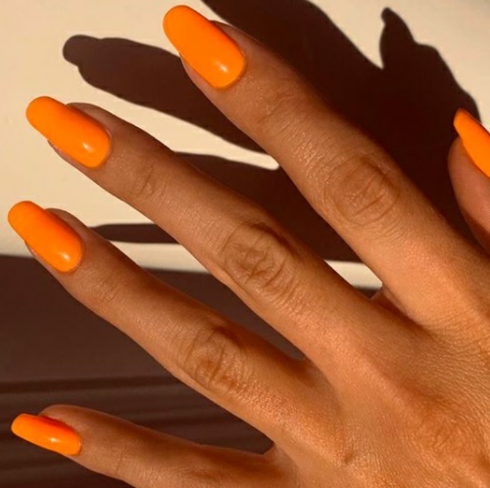 tendencias en las uñas primavera verano 2019, largas uñas pintadas en naranja neón, uñas de gel decoradas en imagines 