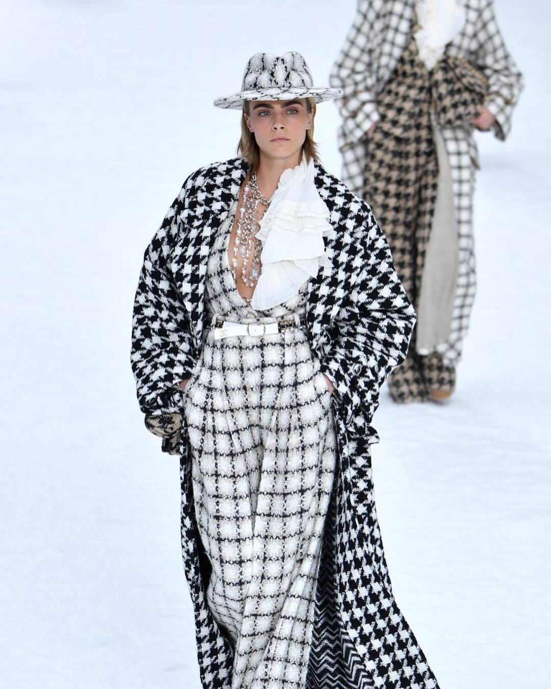 ideas de look invierno 2019, Cara Delevingne con un mono de lana blanco en cuadros negros, chaqueta larga en blanco y negro 