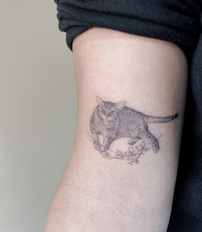 bonito tatuaje de tamaño pequeño en el brazo, tattoo gato con flores, pequeños diseños de tatuajes con fuerte significado 