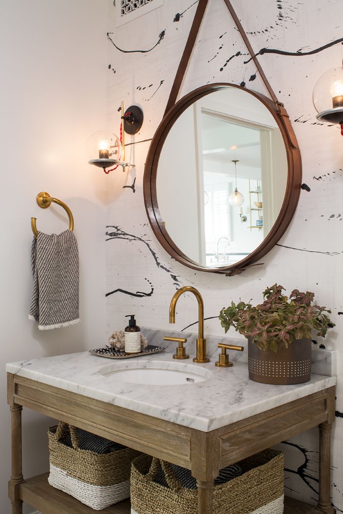 cuarto de baño en estilo bohemio, pequeño lavabo con detalles de madera y mimbre, espejo de forma oval colgado en la pared 