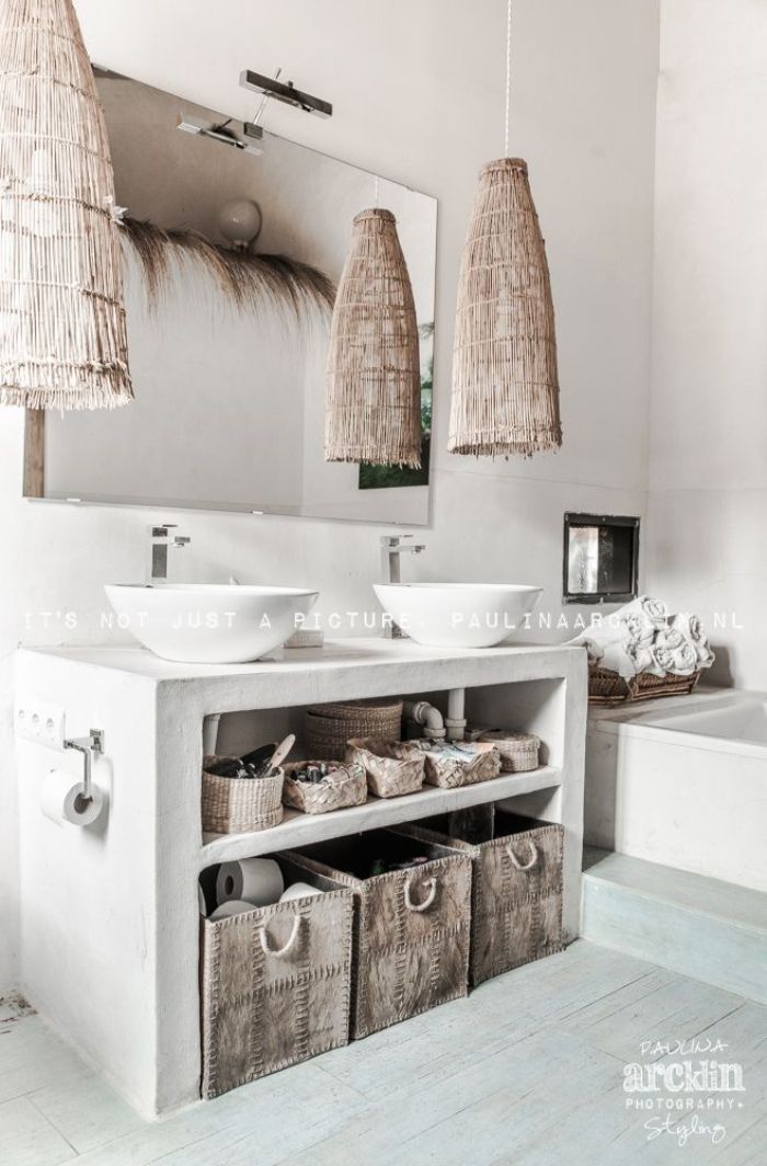 precioso cuarto de baño en estilo rústico, baño decorado en color blanco con detalles de mimbre y grande espejo en la pared 
