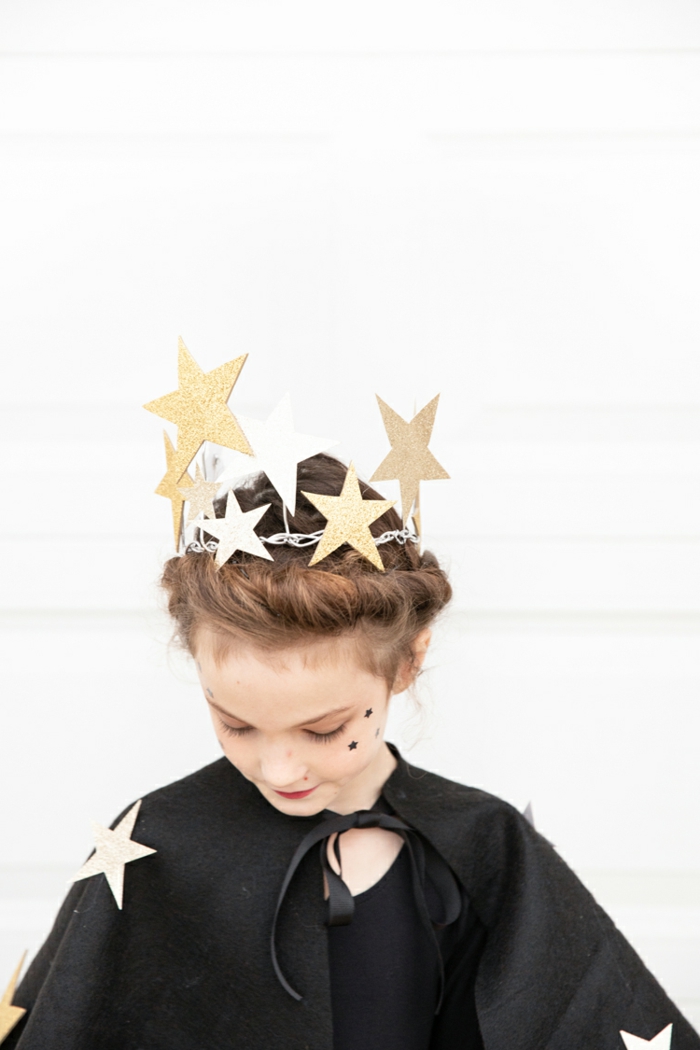 preciosa idea para un disfrace niña, corona de estrellas de cartón en dorado, capa negra de fieltro adornada con estrellas