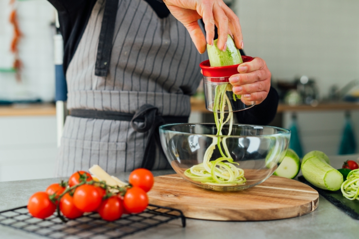 rallar los calabacines con maquina de zoodles en un bol, fotos con ideas sobre como hacer cenas saludables y ligeras