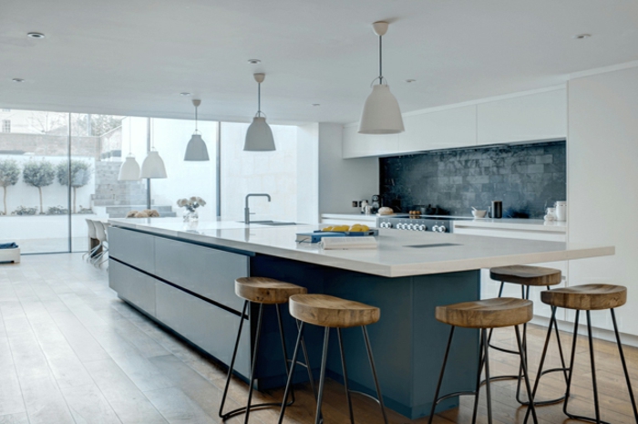 ideas para amueblar una cocina, grande cocina en azul oscuro y blanco con muchas sillas altas y pizarra rústica en la pared 
