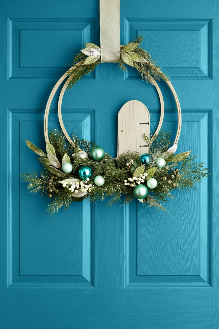 puerta pintada en azul con bonito adorno con ornamentos pequeños en los tonos del verde, decoración clásica para Navidad 