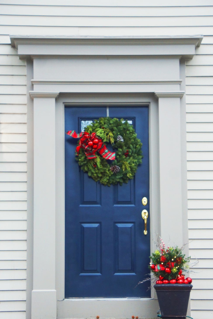fotos de puertas decoradas de Navidad clásicas, detalles decorativos tradicionales, grande corona verde colgada a la pared 