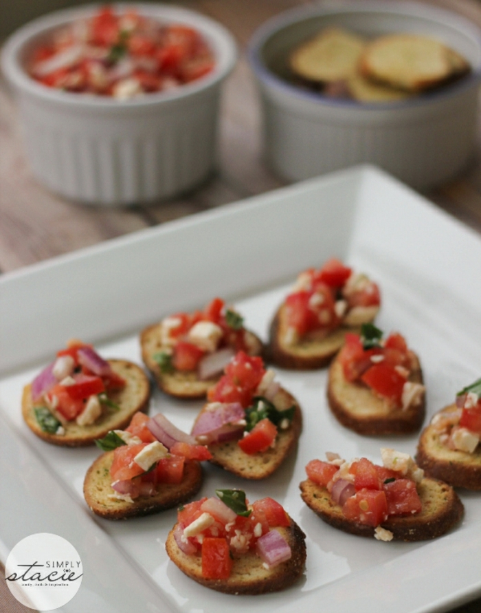 mini tostadas de pan integral, con queso blanco, tomates y cebolla roja, pinchos para navidad y canapes elegantes y ricos 
