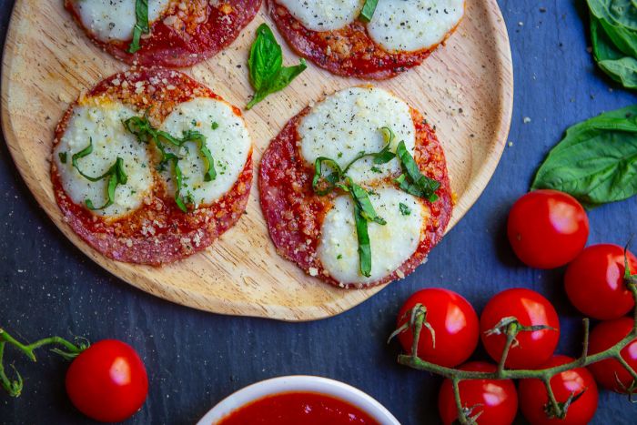 pizza keto sin masa, originales ideas de bocados queso, rebanadas de chorizo con queso hundido, tomates y albahacas 