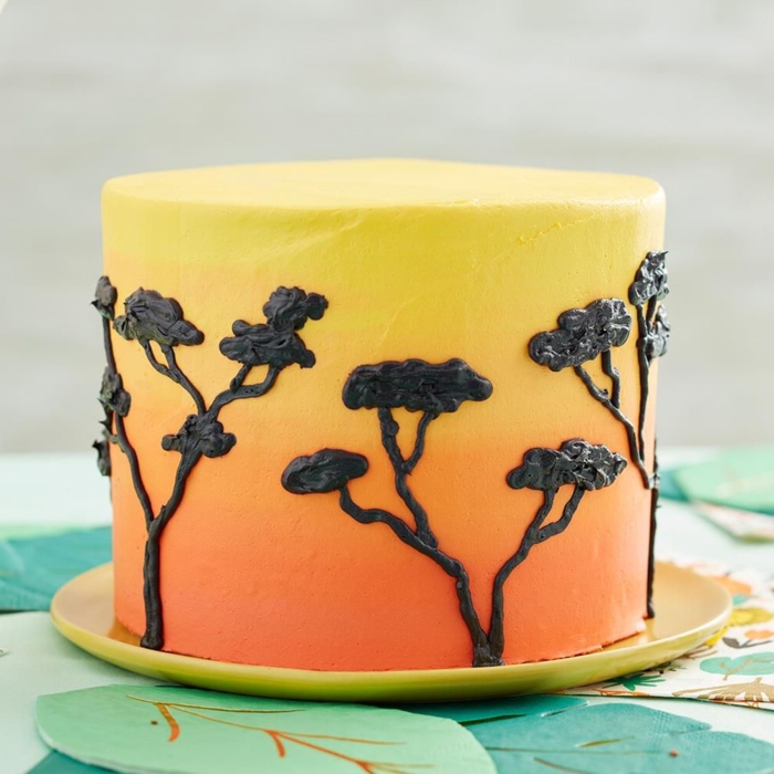 como decorar una tarta con dibujos de Africa, árboles dibujados con glaseado negro, tarta en color amarillo y naranja 