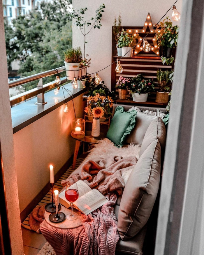 espacio acogedor decorado con guirnalda de bombillas, velas, luces, mantas y cojines, ideas originales de terraza chill out 