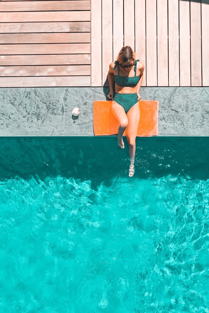 mujer junto a la piscina con bañador verde oscuro gran piscina al aire libre