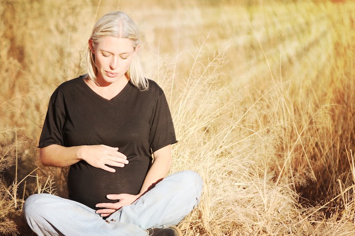 joven madre con cabello rubio sentada en un campo de trigo mujer embarazada en un campo de trigo