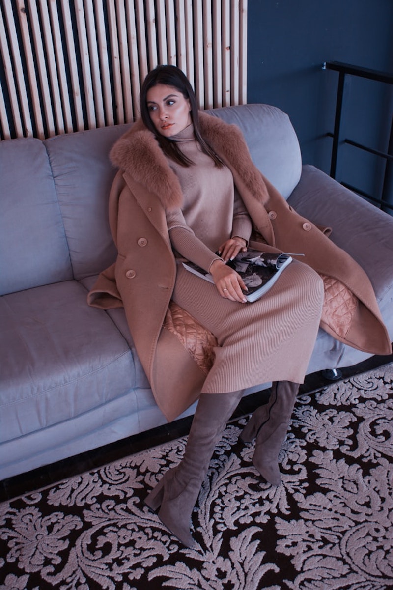 abrigo de mujer en color camel mujer sentada en sofa