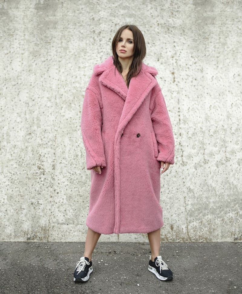 mujer de abrigo rosa con zapatillas pelo marron corto