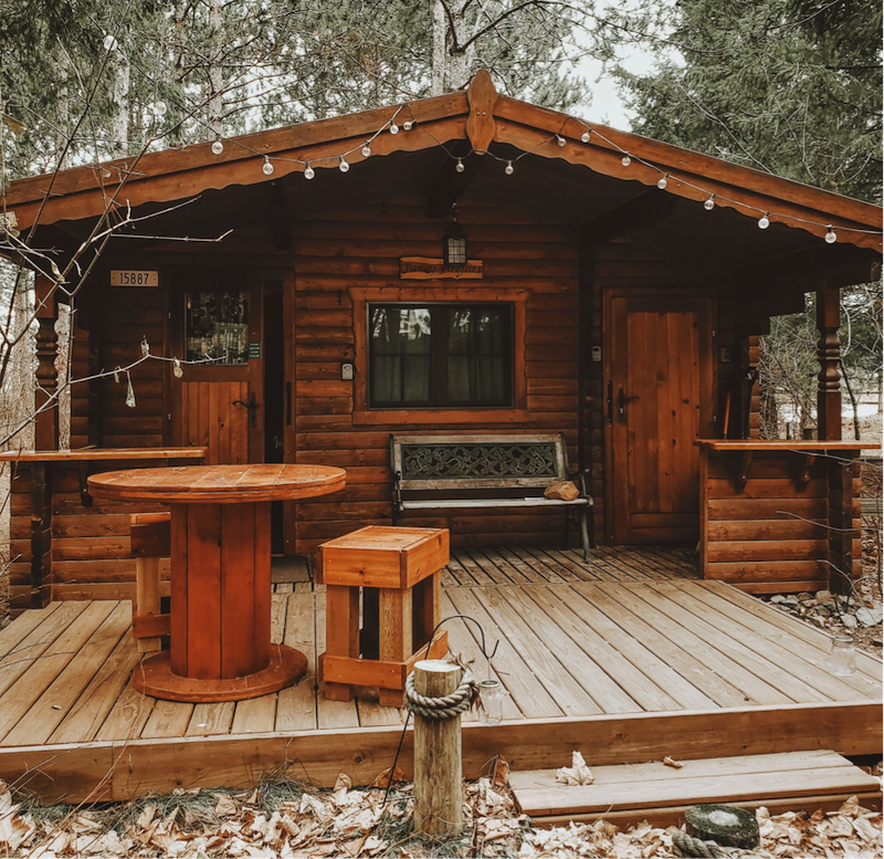 casa de madera en la madera con un banco y un lugar para estar afuera