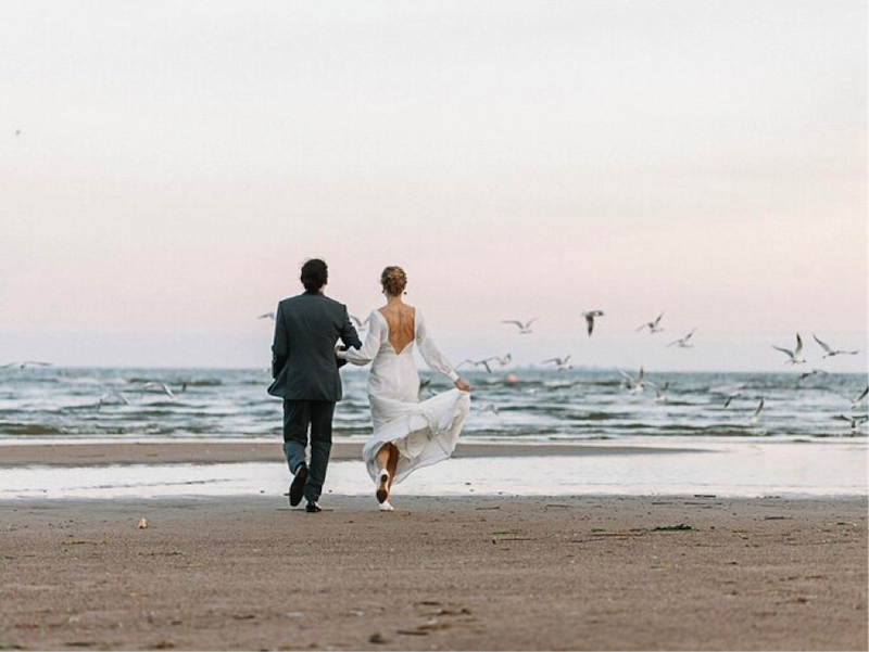 foto de recien casados caminando por la playa
