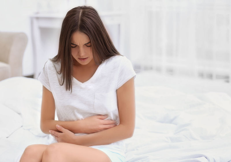 young woman suffering from abdominal pain at home. gynecology concept