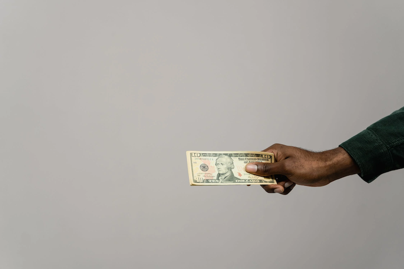 una imagen de un billete y una mano humana sosteniendo el billete