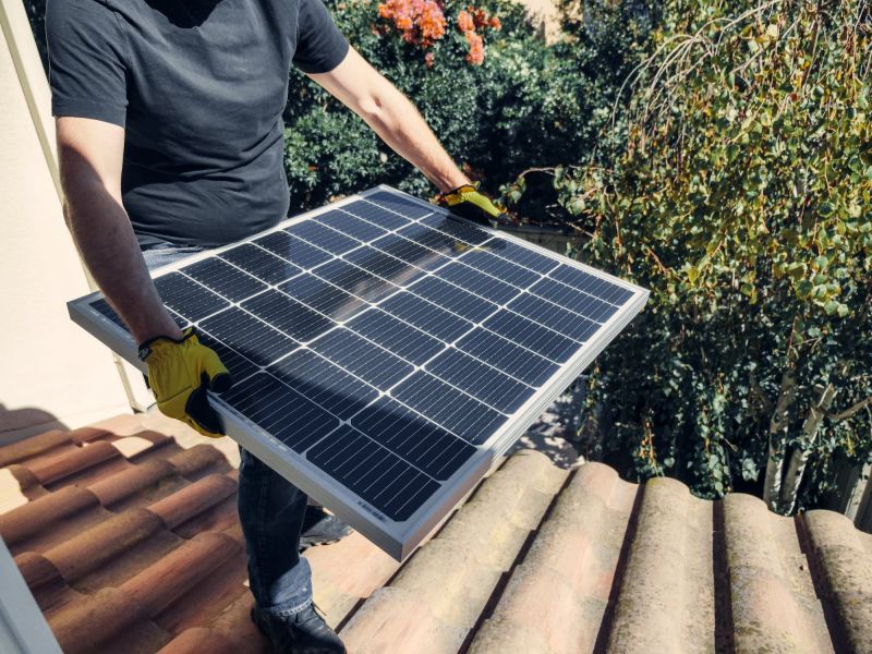 un hombre que sostiene un generador solar en un techo