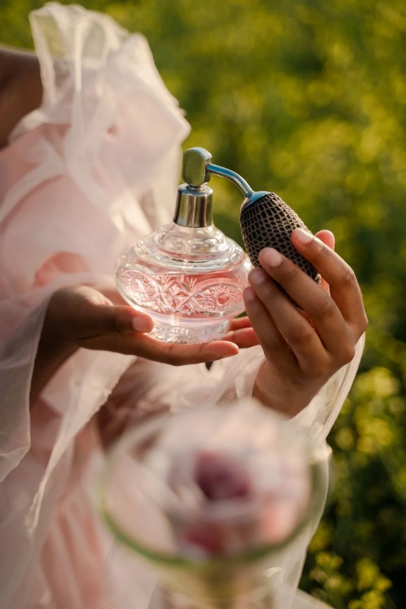 perfume en manos de una mujer que se rocía con una bomba